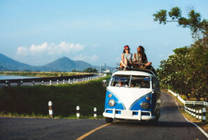 hippy van on the road, with people on top